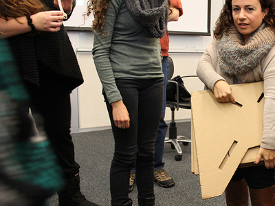 Amanda Cachia, an art historian and curator who also has dwarfism, stands with a cardboard prototype of a lectern for short stature.