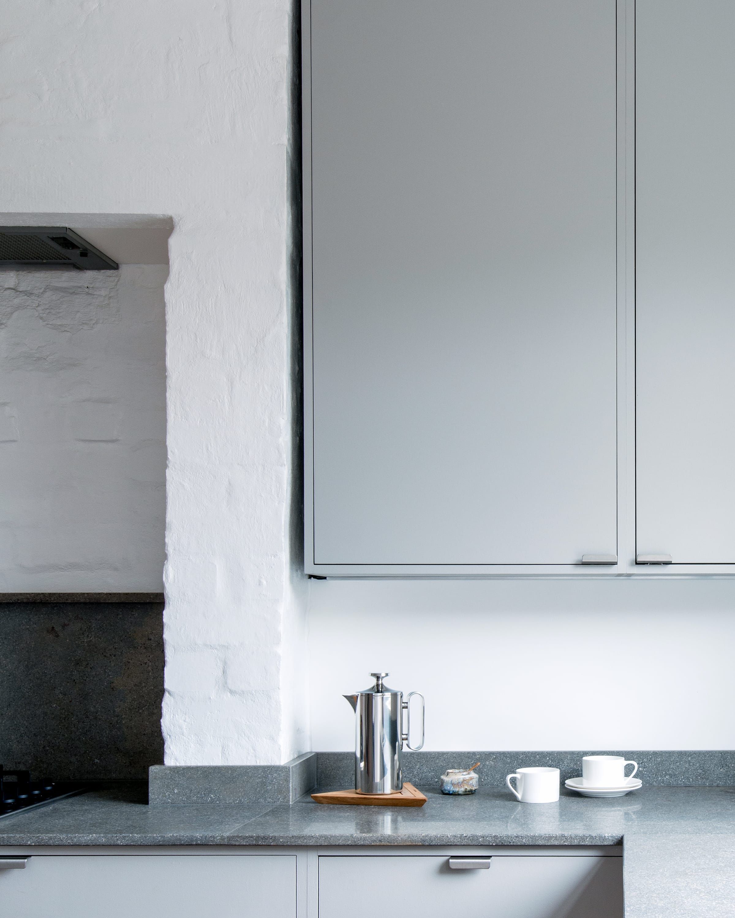 Tall grey kitchen wall units with dark grey limestone worktop. 