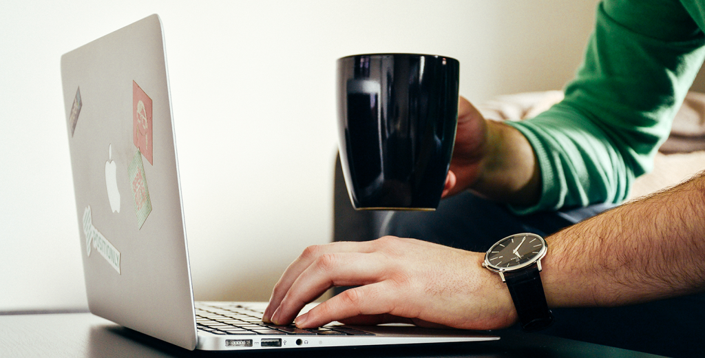 A Laptop is top of the list for any IT contractor A man using a laptop and drinking a coffee