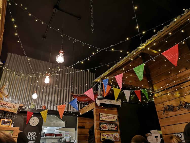 The cieling of a restaurant in York covered in multi-coloured bunting, fairy lights and large industrial light bulbs.