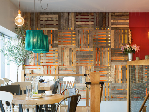 Artistic cafe style with round wooden tables and black and white chairs in front of wooden pallet wall design   Skype background