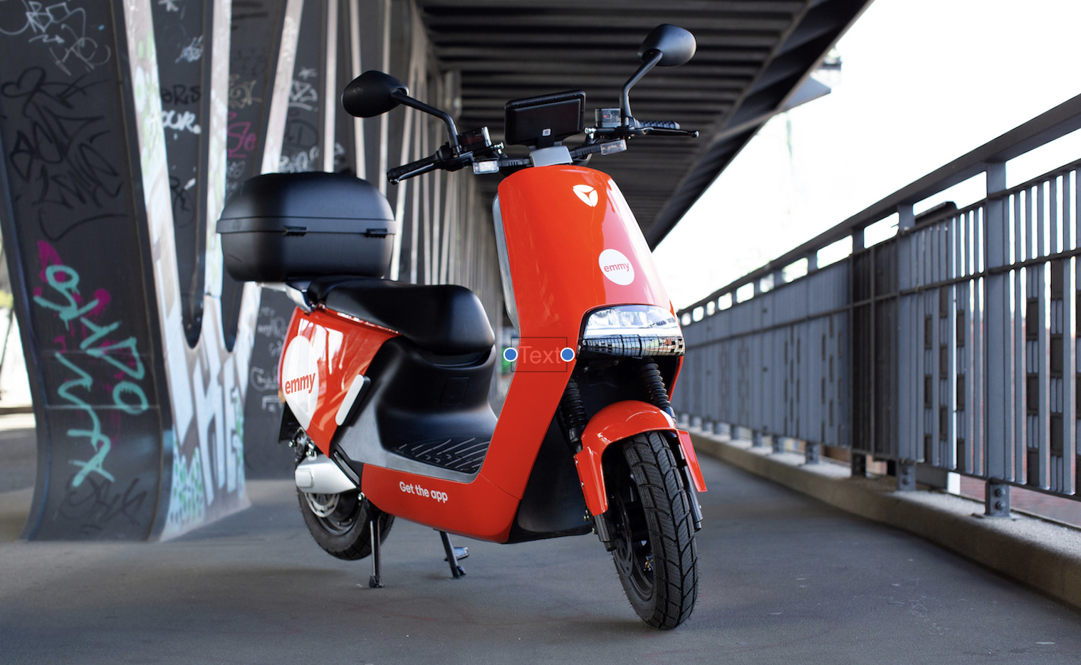 A emmy e-moped standing in the middle of a walking bridge.