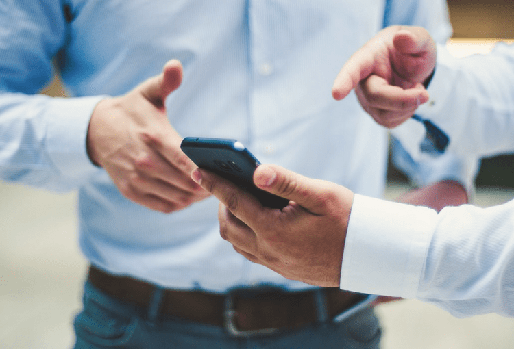 App-Programmierung für Smartphones Männer in blauen Hemden zeigen auf App-Programmierung auf ihrem Smartphone