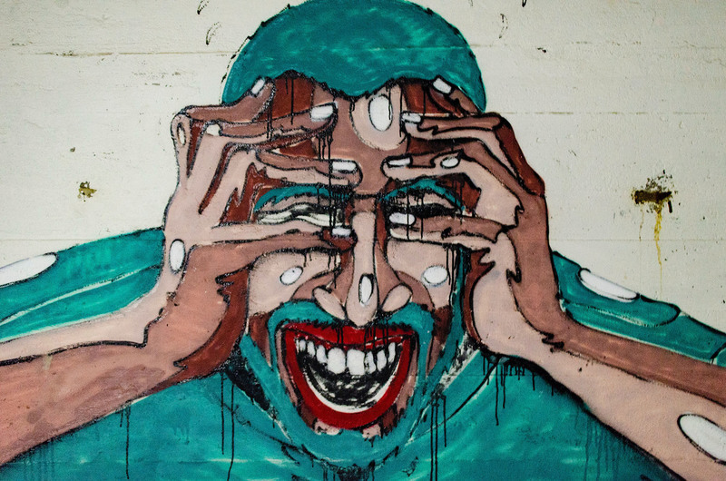 Um grafite de um homem com as mãos no rosto dando um grito.