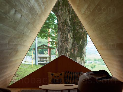 Cosy interior of unusual narrow triangular structure with wood panelling and large window looking onto countryside view Zoom background