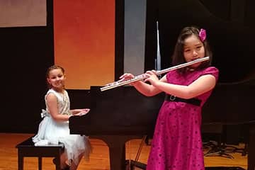 two students performing piano and flute