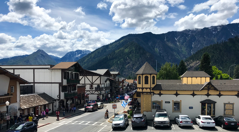Leavenworth, WA: a cozy street of Bavarian-style buildings with 3 mountains looming close behind