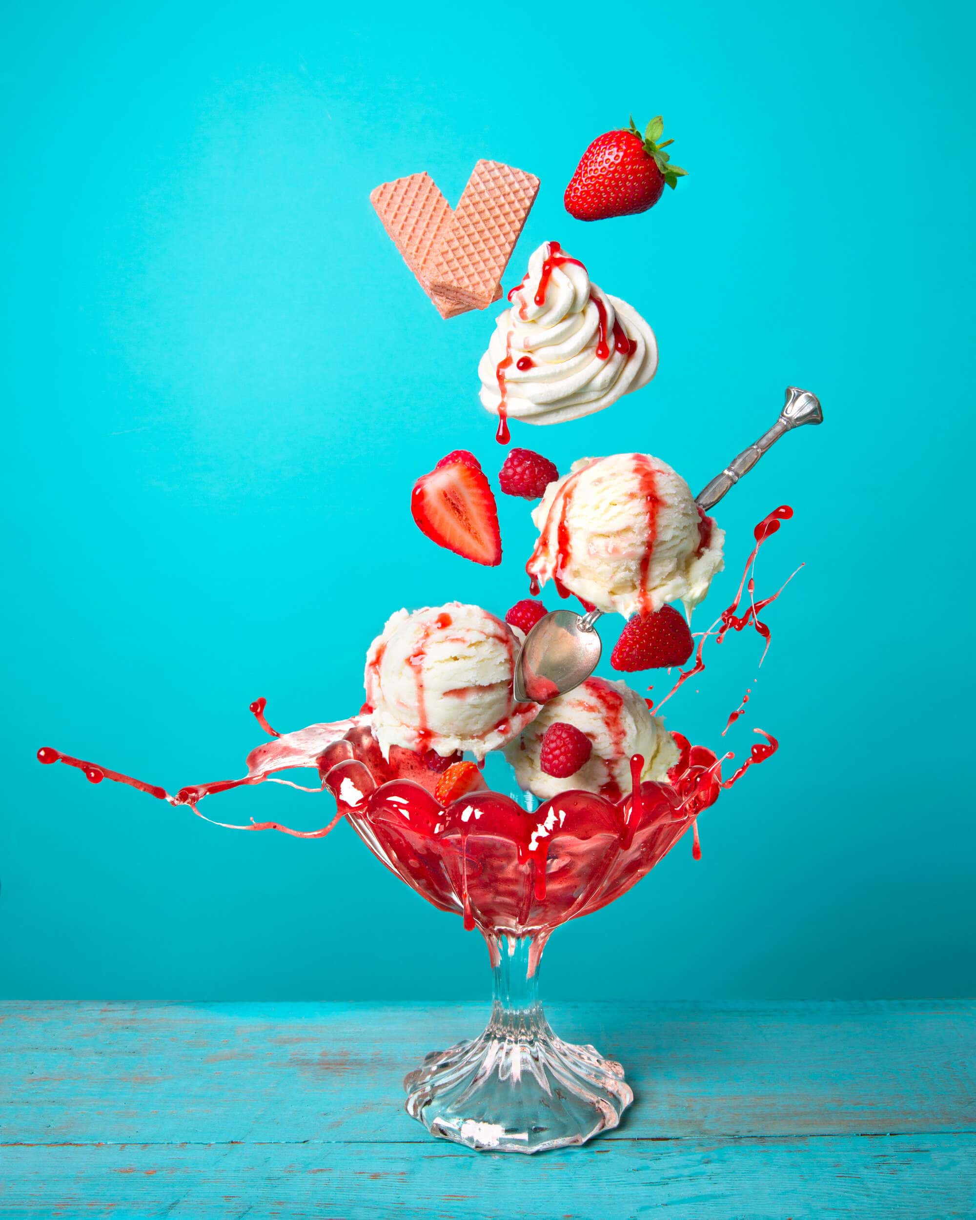 ice cream, strawberries and cream splashing into a bowl.
