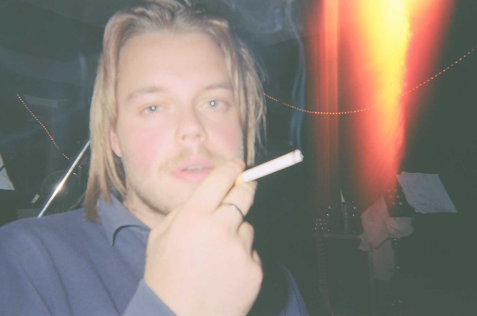 Ein Bild des Bassisten der Band mit einer Zigarette in der Hand.
