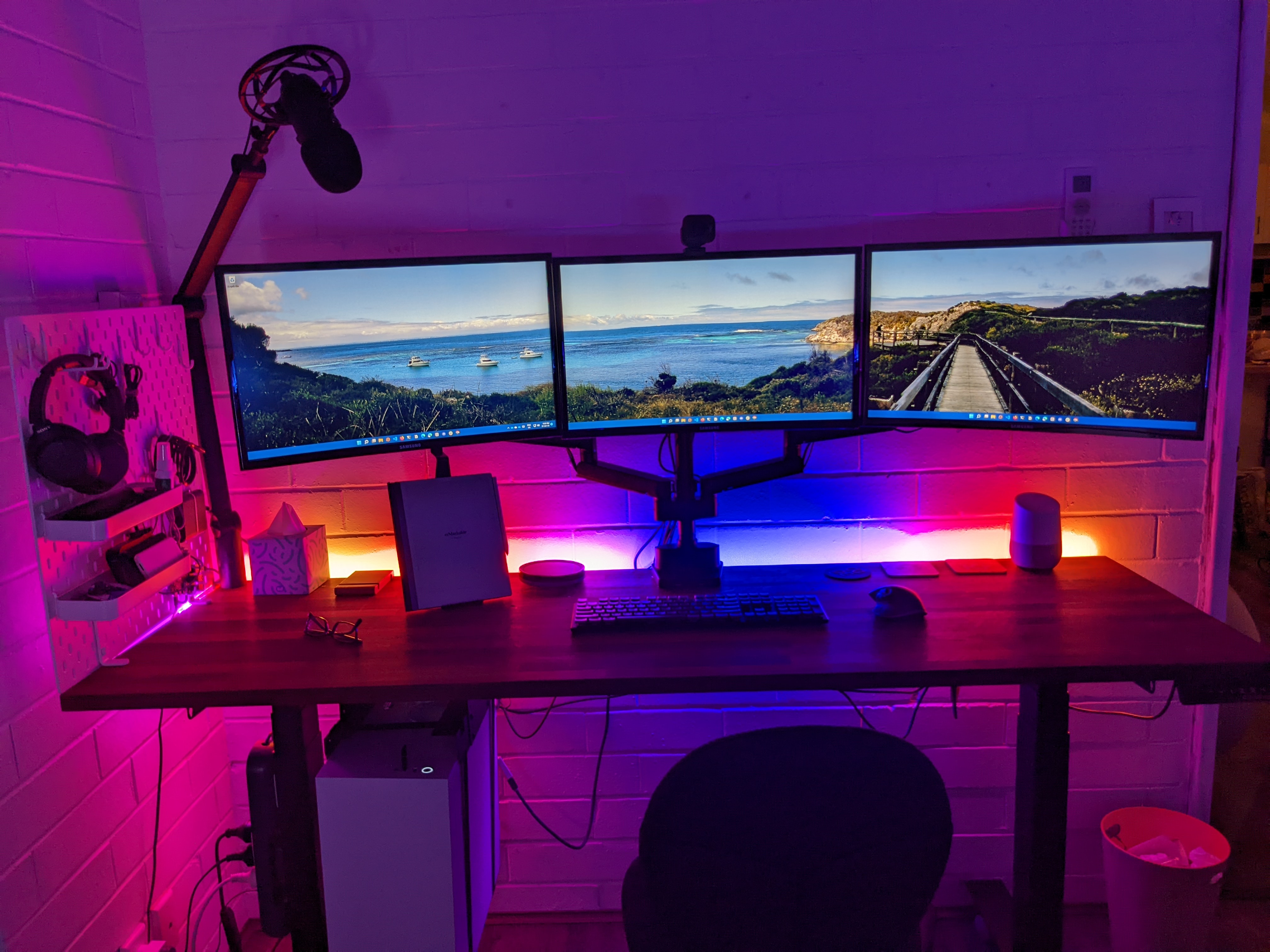 Assembled desk with three monitors, this time dimly lit to show the rainbow LED lighting on the back of the desk