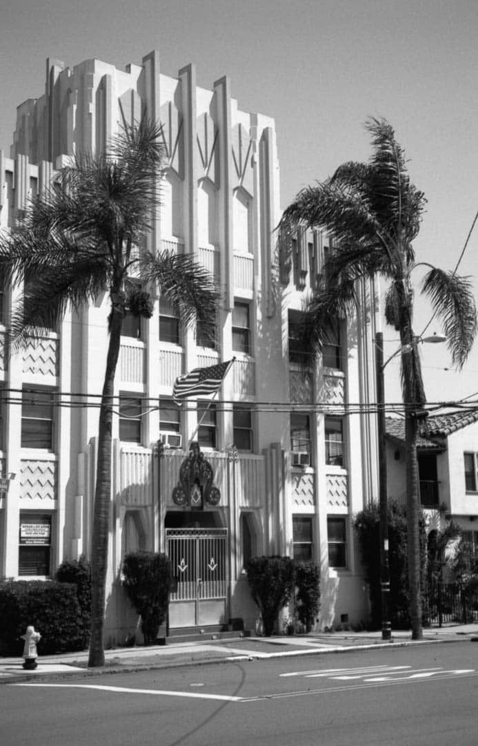 An art decco building with two palm trees out front in San Diego