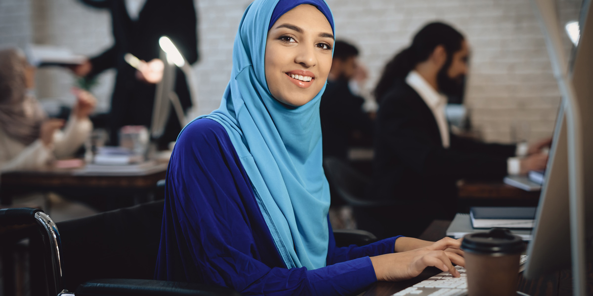 What's the difference between data science, data analytics, and machine learning? A woman sitting at a desk, typing on a keyboard, smiling at the camera