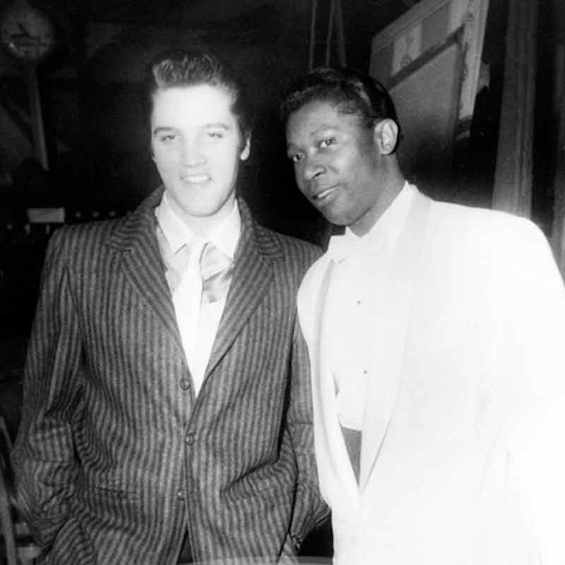 A photo taken by Ernest Withers of Elvis Presley wearing a pinstripe suit next to B.B. King wearing a white suit.