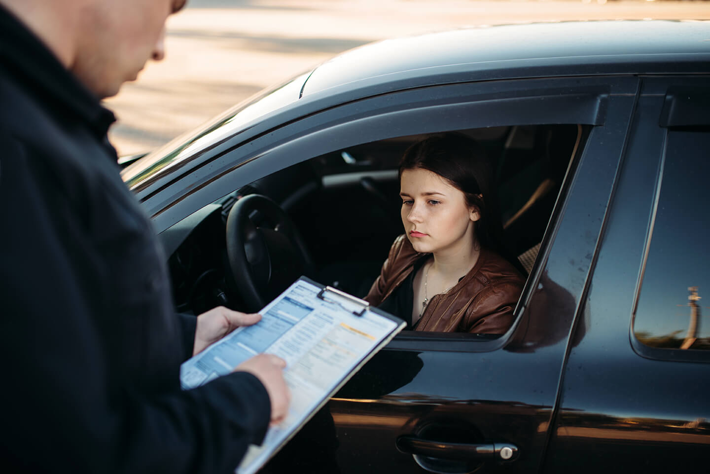 a driver being given a paper traffic citation by an officer