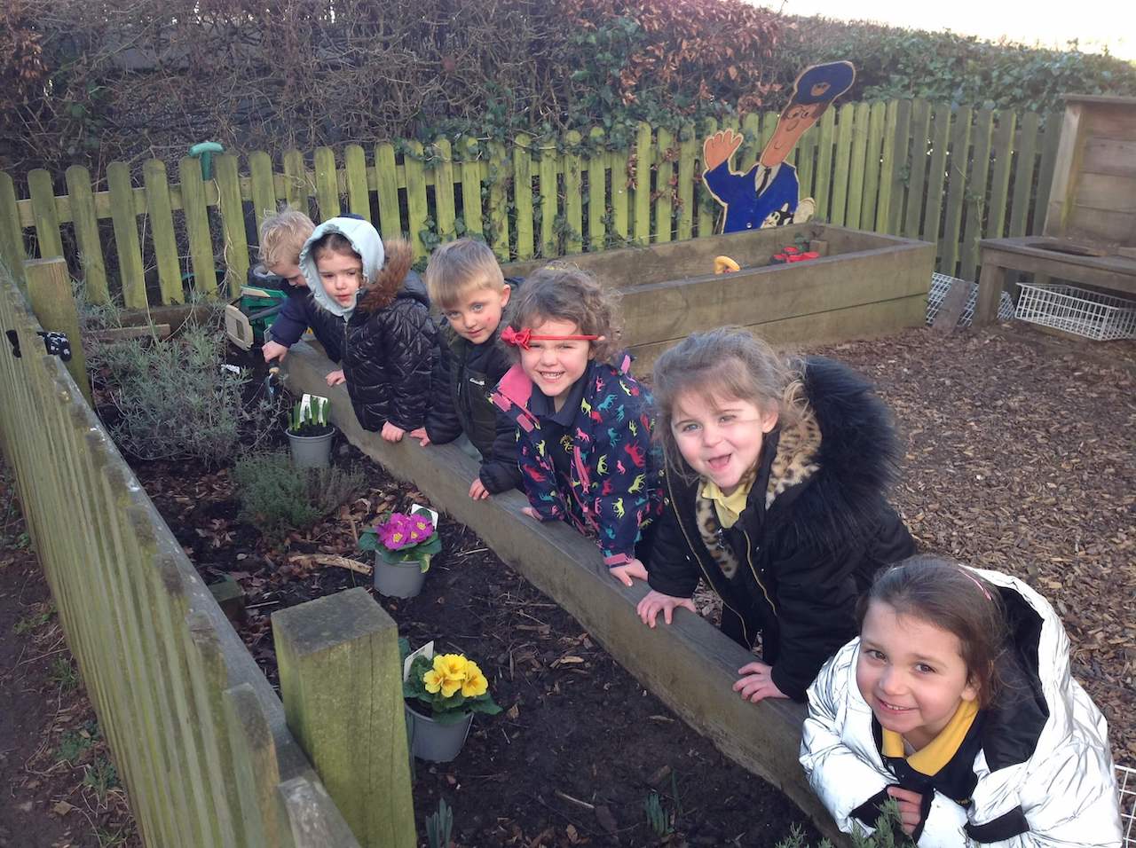 Six happy children potting plants in the Pre-school garden