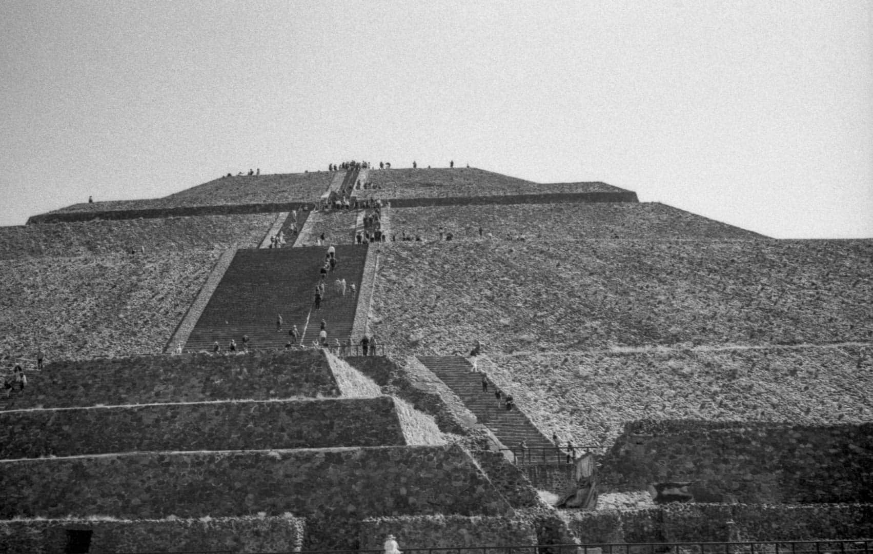 A large Teotihuacan pyrimid with many people walking up