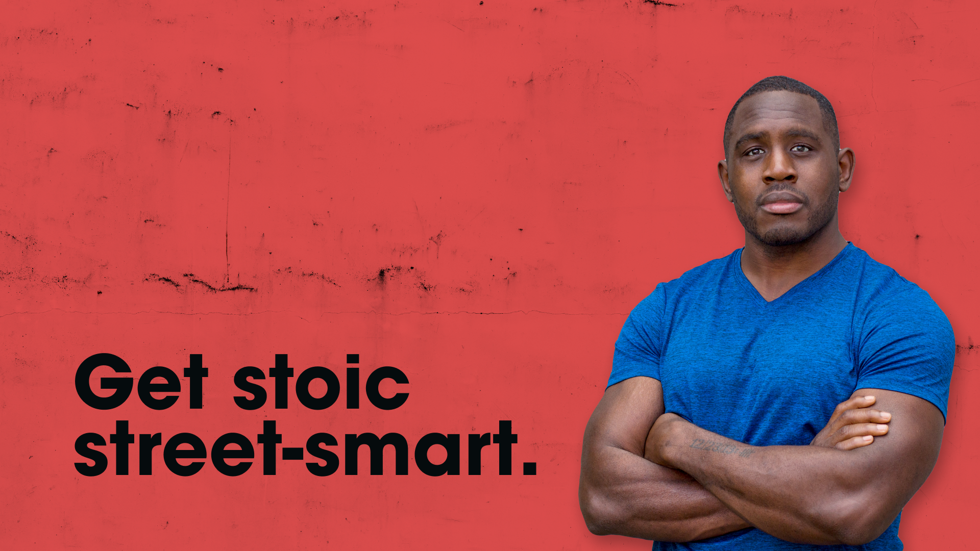 Photo of Ed Latimore standing in front of a red concrete wall with his signature tagline, “Get stoic street-smart,” printed on top of it