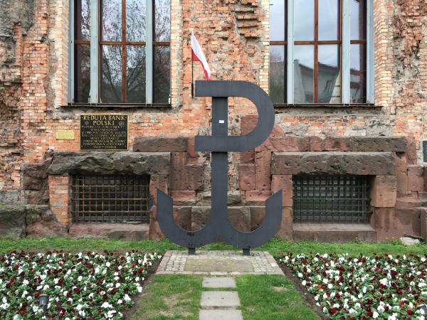 That symbol is the sign of the Warsaw Uprising - it is common to see it in Warsaw. ("Anchor," formed from the letters "P" and "W," for Polska Walcząca which means "Poland Fights")