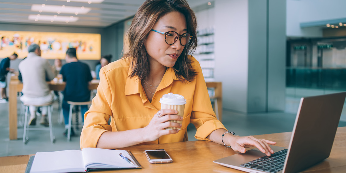 What is a decision tree, and what are decision trees used for? A data analyst sitting at a desk looking at a laptop, holding a cup of coffee
