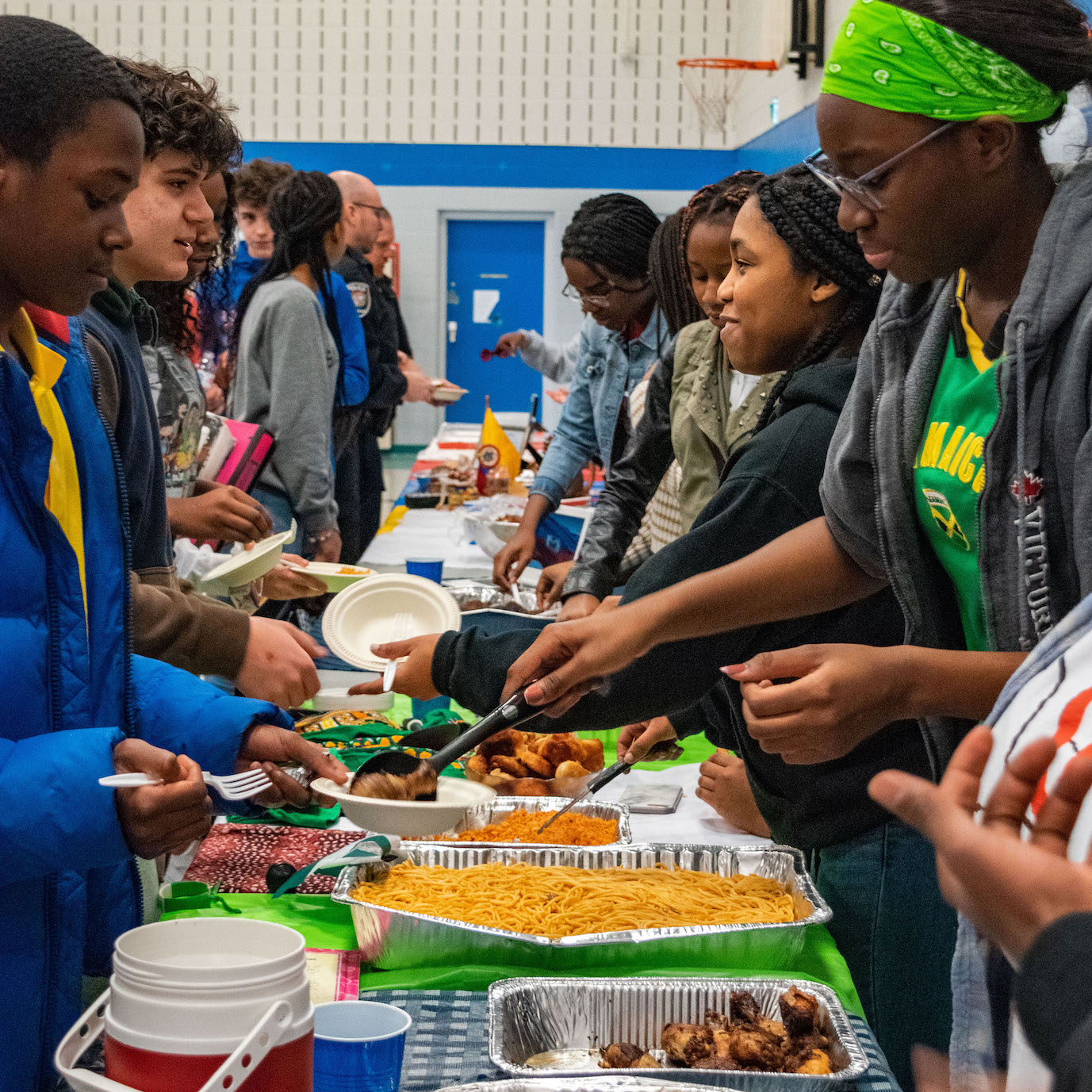High school students handing out food to other high school students during a food fair.