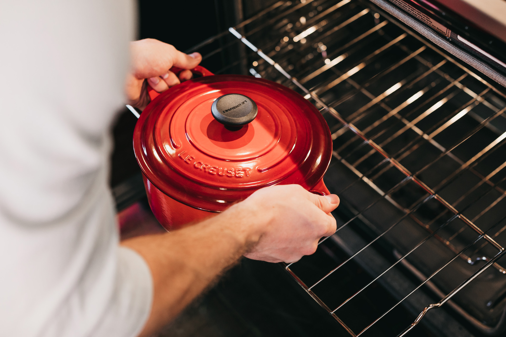 Man puts Le Creuset pot into sparkling clean oven