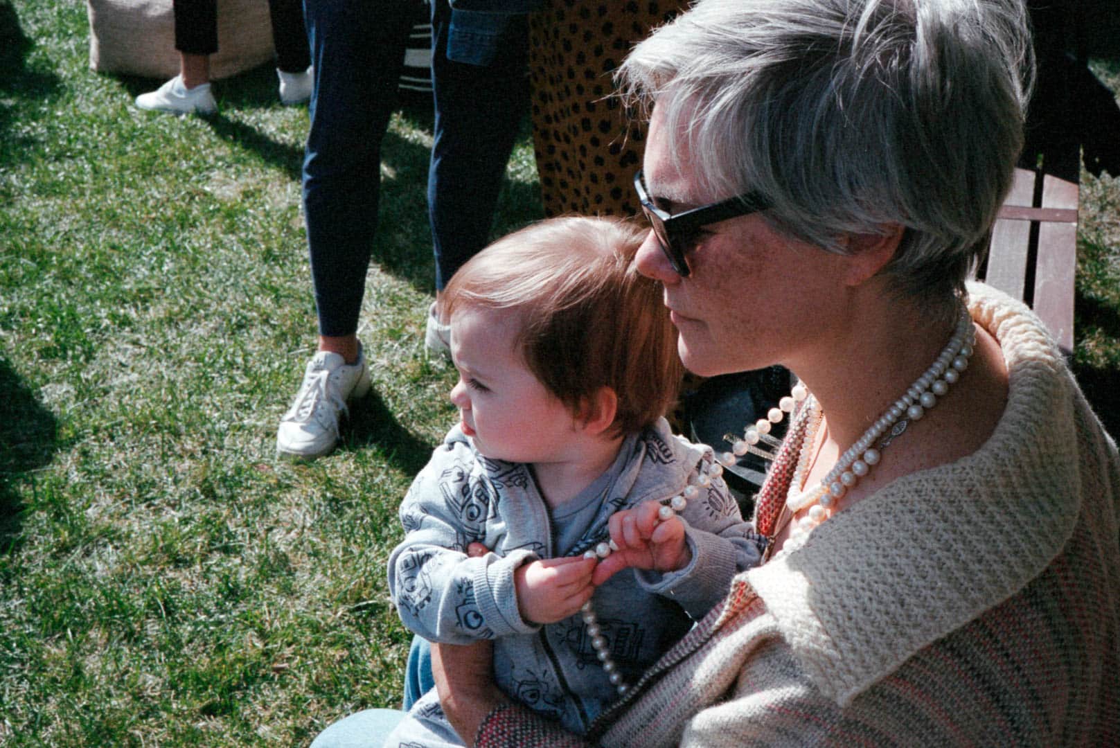 A woman and a baby sitting at a garden party