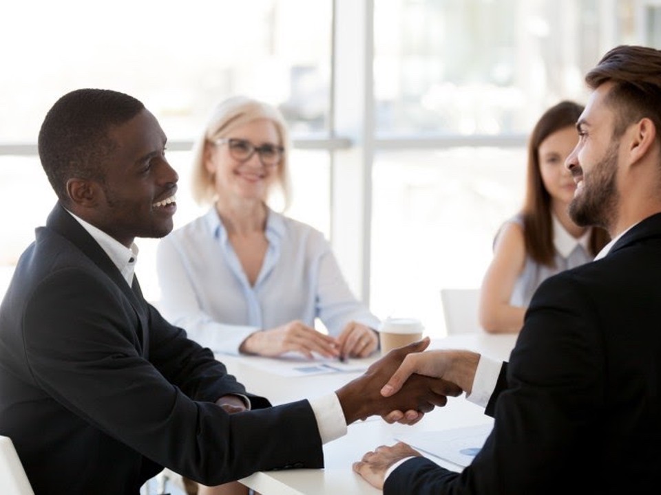 A candidate for a teaching job shakes hands with an interviewer during a group interview.