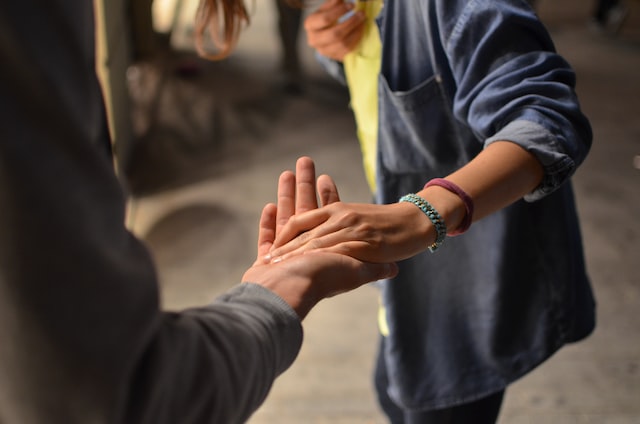 Younger person with bracelets taking someones hand