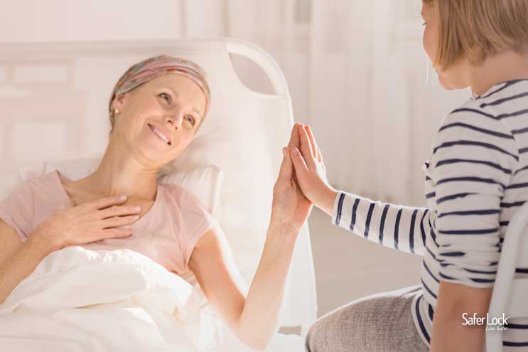 Image of a smiling cancer patient in a hospital bed holding hands with her young daughter.