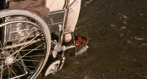 An animated gif of a scene from the movie 'Hana-bi' of the tide washing along the bottom of a wheelchair.