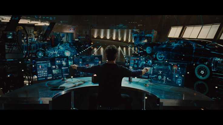 Tony stark in front of multiple screens that have various interfaces and abstractions