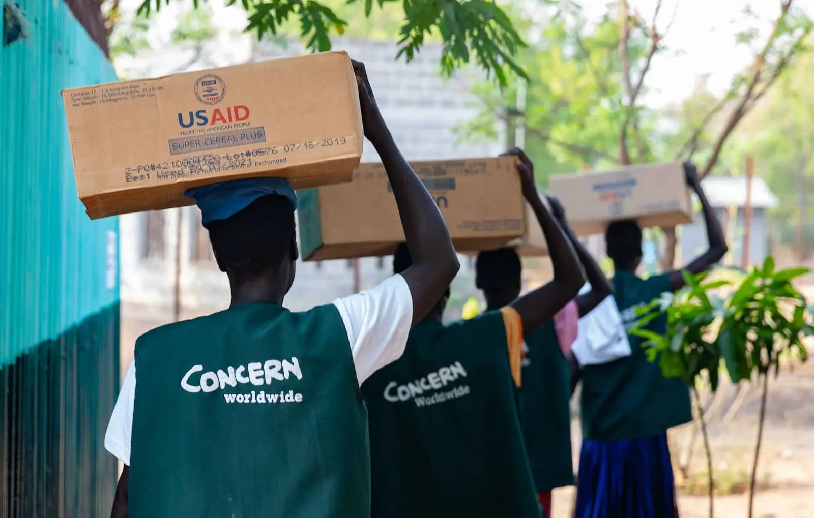 women in Concern vests carrying USAID materials