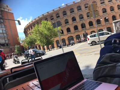A laptop on a table outside in a city next to an ancient colloseum
