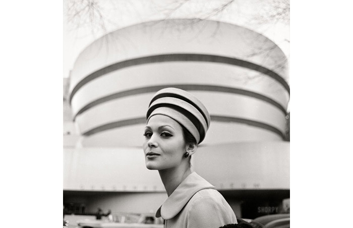  black and white photo of a woman model wearing a hat in front of the guggenheim museum