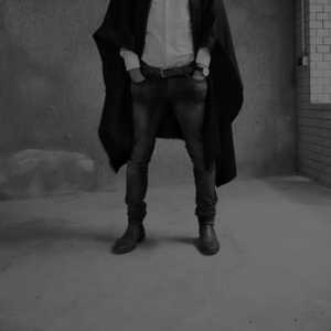 Sexy queer man in a black poncho. Avant garde fashion. Haute de couture. Tribal postapocaliptic fashion.