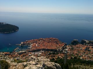 Terracotta rooftops in the Dubrovnik old town viewed from above. Island of Lokrum in the distance.