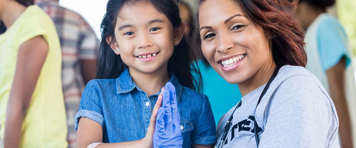 Image of smiling medical professional volunteering their time and giving happy little girl a high-five. Find out what you can use CAPTA funds for.