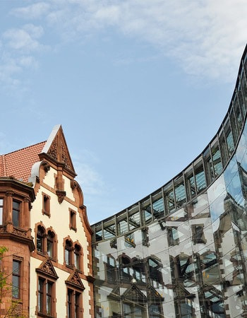 Photo of an old house and a modern glass building in the background, presumably in the city of Dortmund