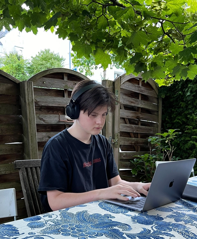 Oli sitzt im Garten und töggelet auf seinem Laptop.