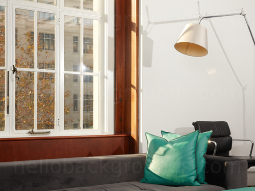 Calm office space with street views containing modern style grey sofa and black padded office chair Zoom background