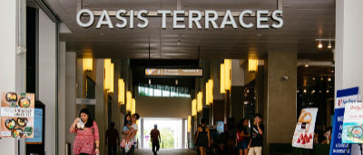 A photograph showing eight people walking through the ground floor of Oasis Terraces, an integrated shopping mall and community centre.