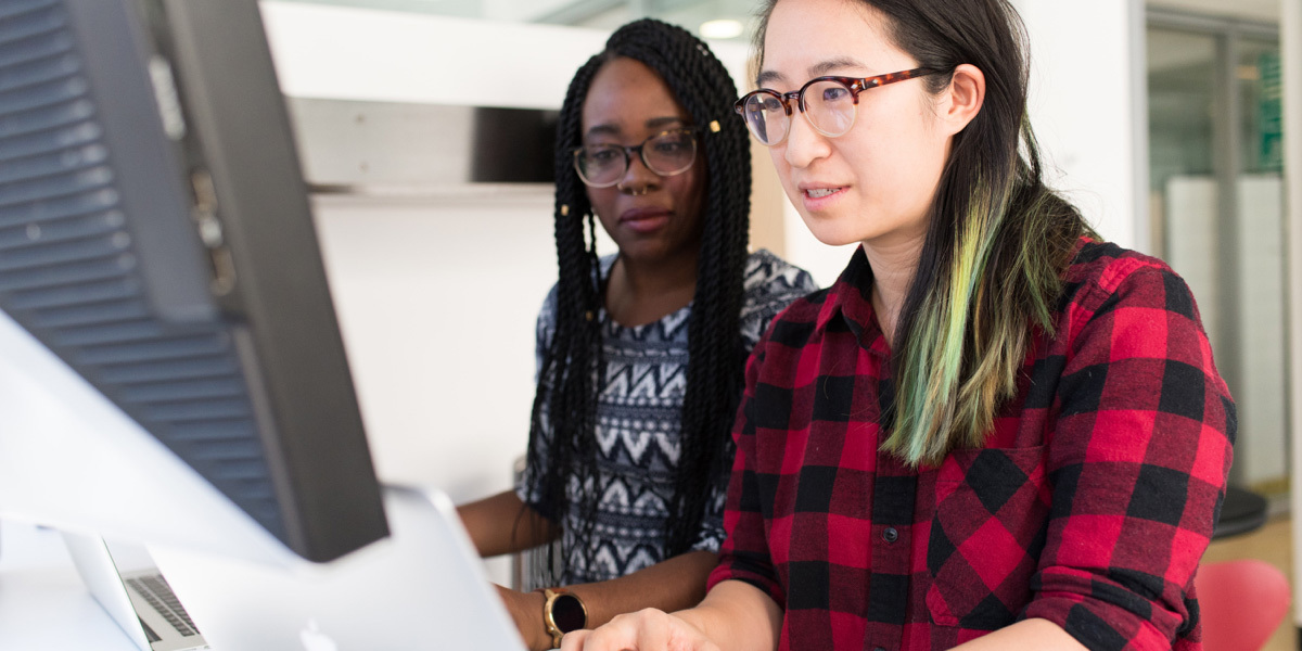 What do digital designers do? Two women digital designers sitting in front of the same laptop