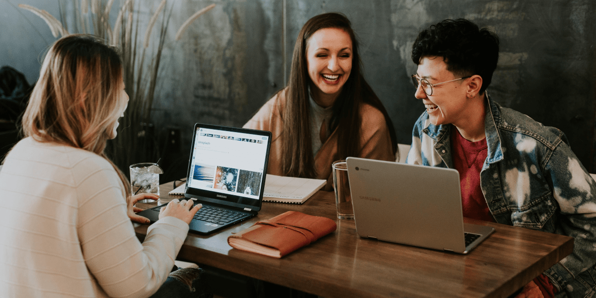 What are the different types of data visualization? Three data analytics students sitting at a wooden table, laughing, with laptops in front of them