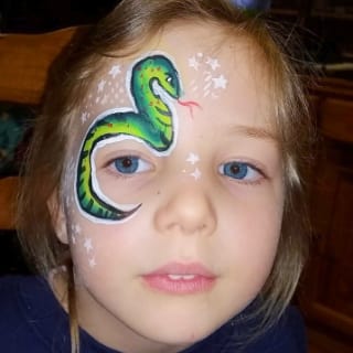 A girl with a green snake and little white stars painted around her right eye. Click to view at full size.