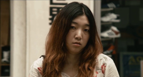 A close-up screenshot of Ichiko (played by Sakura Ando) apathetically looking at the camera in the film '100 Yen Love'.
