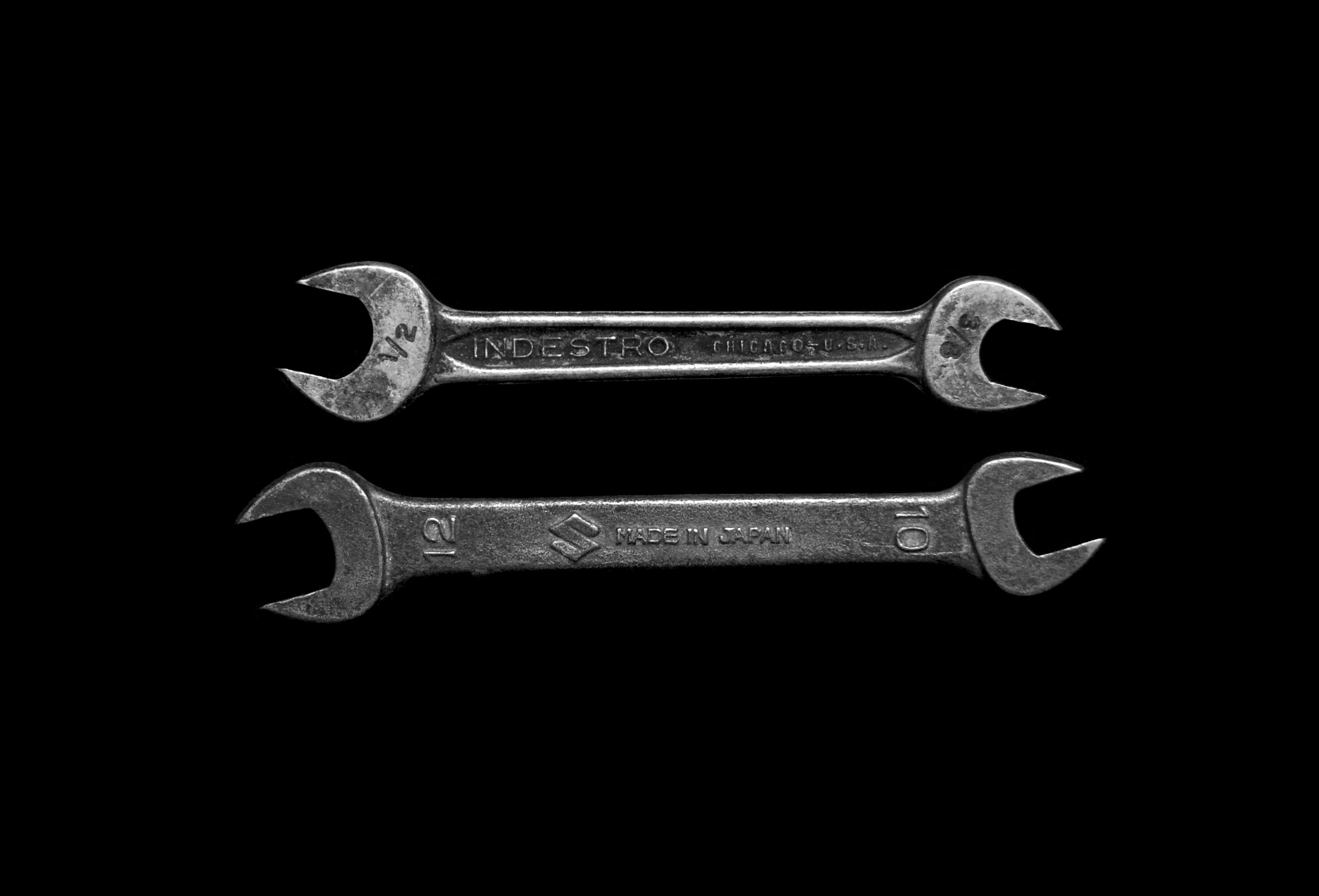two old-fashioned box wrenches against a dark background