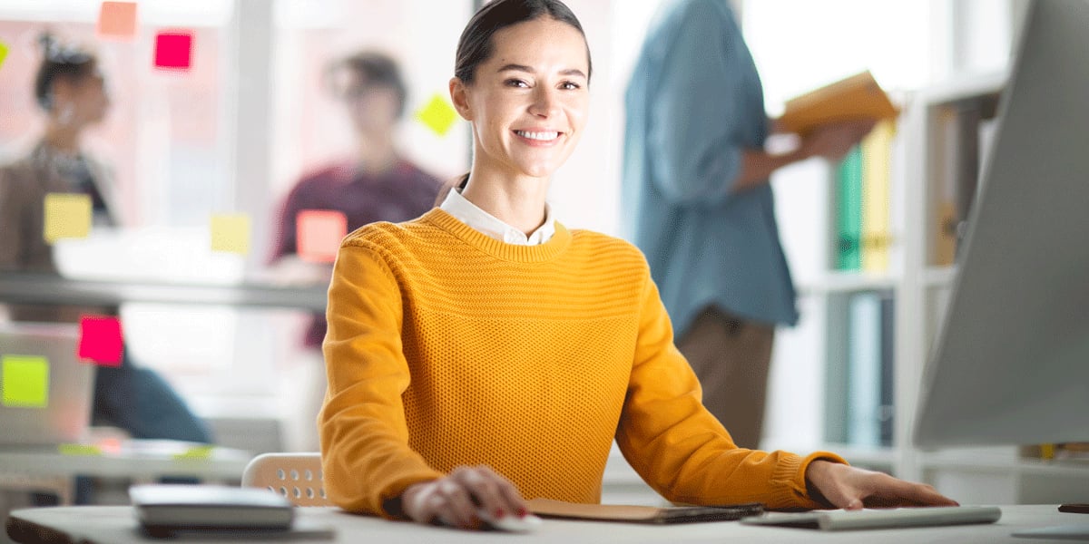 What's the difference between a data analyst and a data scientist? A data analyst sitting at a desk, smiling A data analyst sitting at a desk, smiling towards the camera