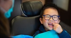 A smiling boy sitting in a dentist's chair at Glenbrook Dental