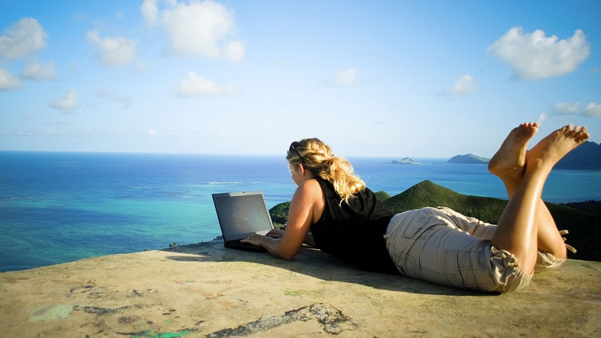 Lady working overlooking a cliff at the beach.