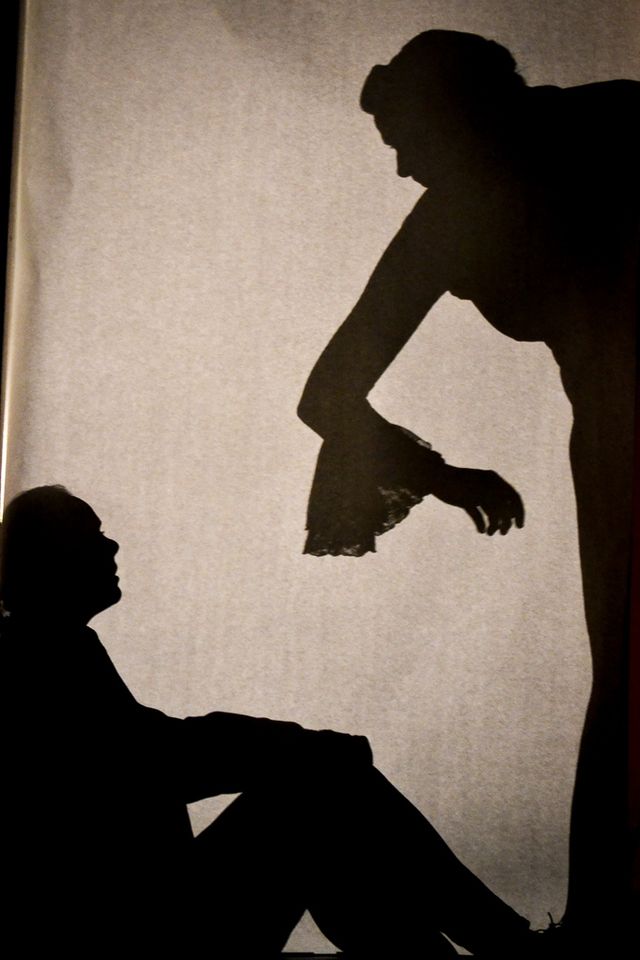 Silhouette behind a paper screen,
Jane offers her arm to Mr. Rochester (Frank)
who is on the ground.
